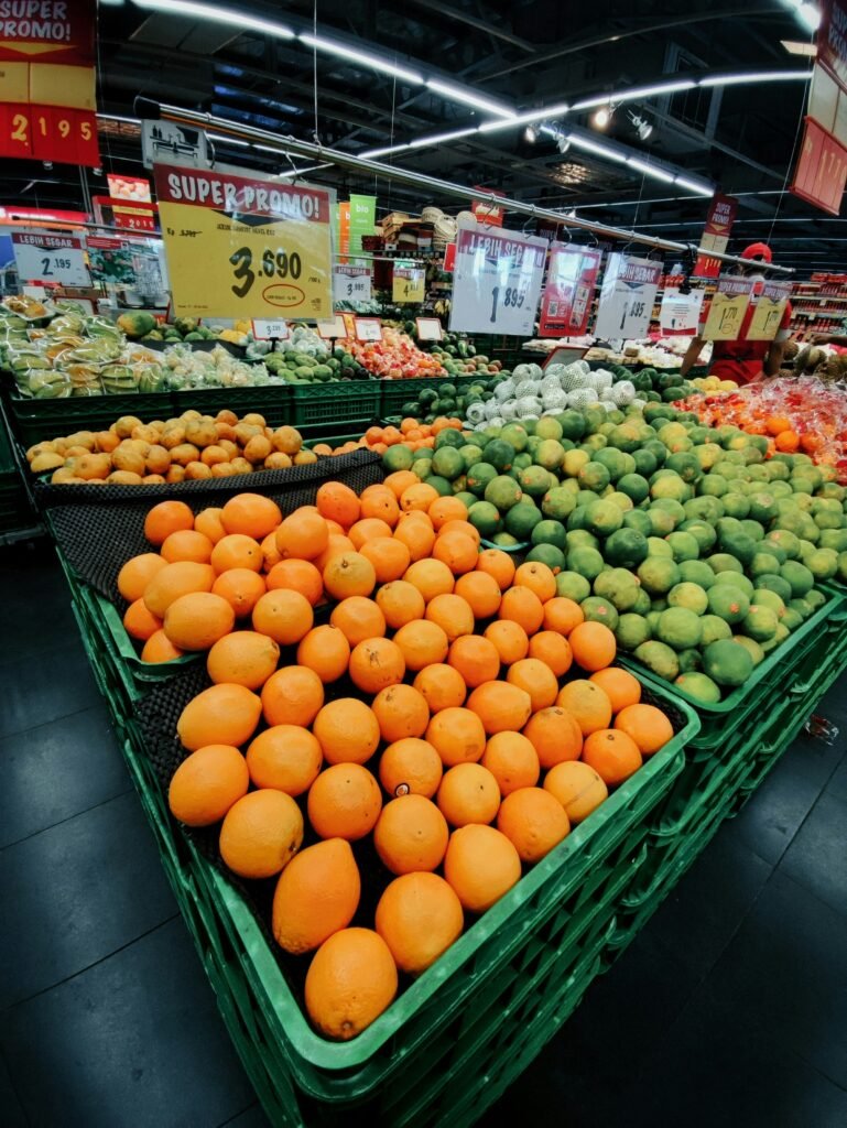 a produce section of a grocery store filled with oranges and melons a produce section of a grocery store filled with oranges and melons