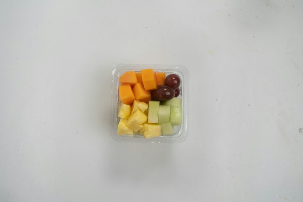 A plastic container filled with cut up fruit
