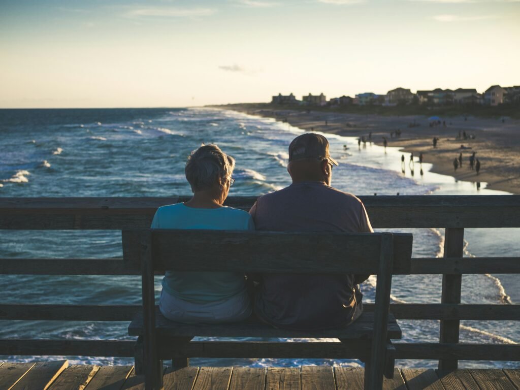 man and woman sitting on bench in front of beach man and woman sitting on bench in front of beach